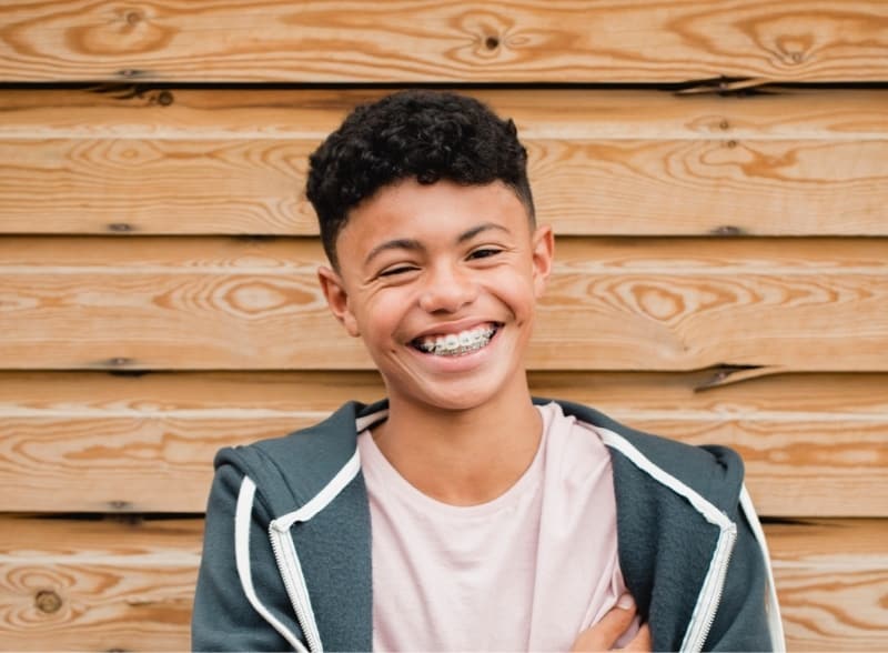 Smiling boy with braces in front of wall